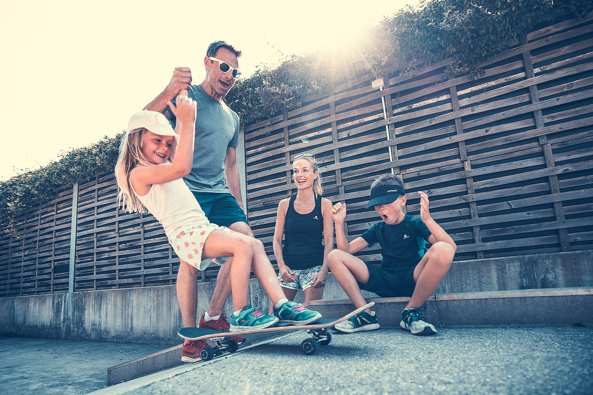 Vater hilt Tochter beim Skateboarden