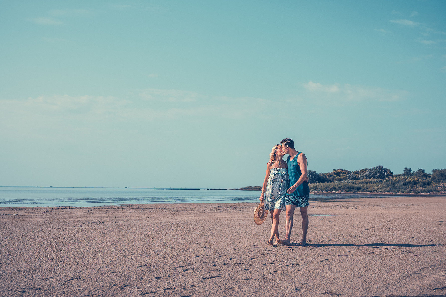 Coppia si bacia durante una passeggiata romantica sulla spiaggia